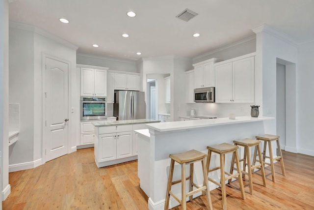 kitchen with stainless steel appliances, light hardwood / wood-style floors, kitchen peninsula, and white cabinetry