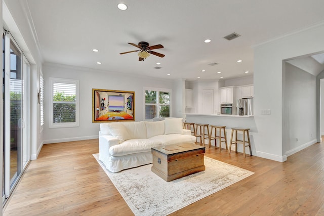 living room featuring crown molding, light hardwood / wood-style flooring, a wealth of natural light, and ceiling fan