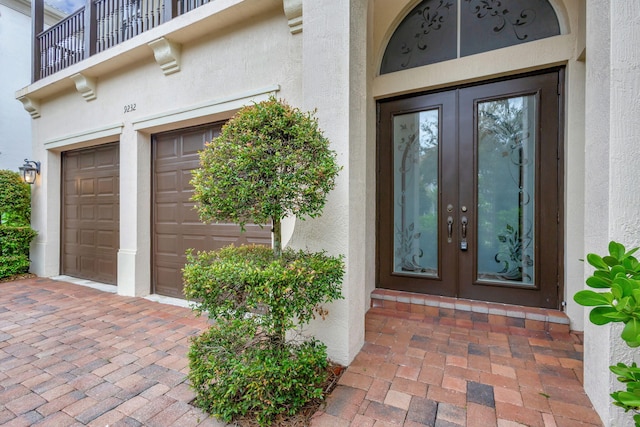 property entrance featuring a garage, french doors, and a balcony