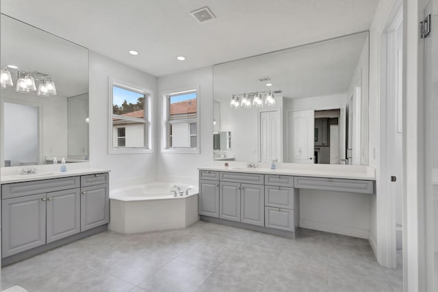 9232 Nugent Trl, West Palm Beach, FL 33411 - full bathroom featuring two vanities, a chandelier, a bath, tile patterned flooring, and recessed lighting