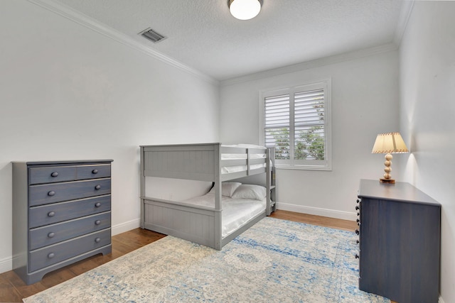 bedroom with a textured ceiling, dark hardwood / wood-style floors, and ornamental molding