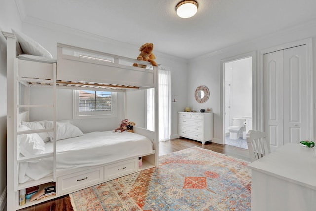 bedroom featuring ensuite bath, a closet, crown molding, and dark hardwood / wood-style flooring