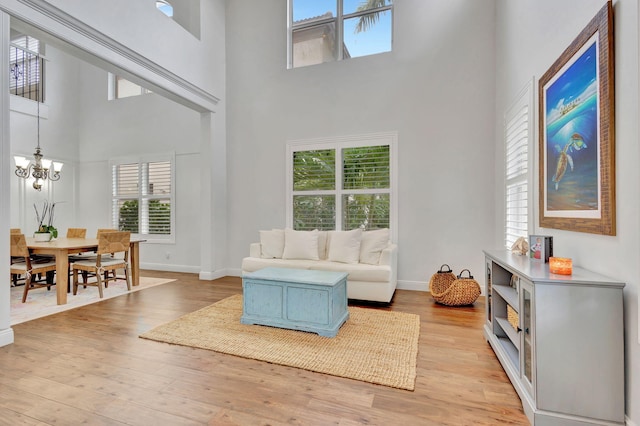 living room with a towering ceiling, light hardwood / wood-style floors, and a chandelier