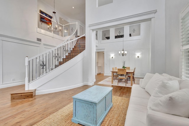 living room with wood-type flooring, a notable chandelier, and a towering ceiling