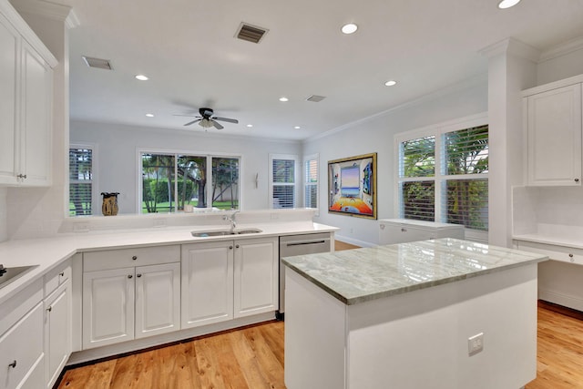 kitchen with kitchen peninsula, a kitchen island, light hardwood / wood-style floors, and white cabinets