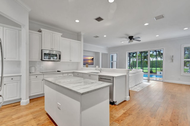 kitchen featuring light hardwood / wood-style floors, ceiling fan, white cabinets, appliances with stainless steel finishes, and a center island