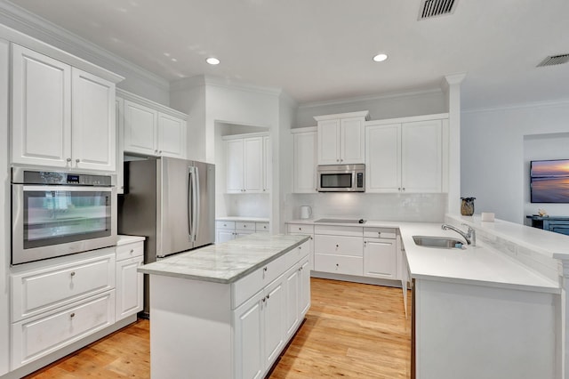 kitchen featuring white cabinets, sink, light hardwood / wood-style floors, kitchen peninsula, and appliances with stainless steel finishes