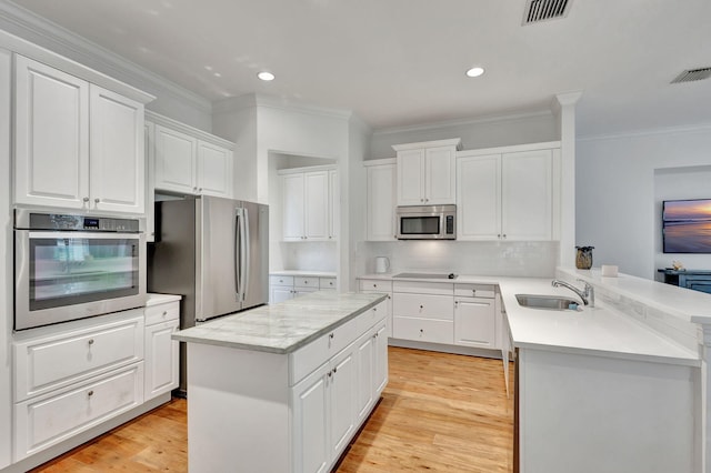 9232 Nugent Trl, West Palm Beach, FL 33411 - kitchen with stainless steel appliances, a peninsula, ornamental molding, white cabinets, and a center island