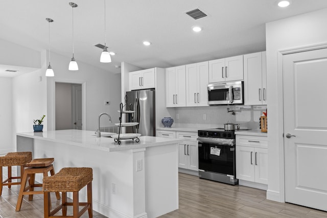 kitchen featuring appliances with stainless steel finishes, pendant lighting, white cabinetry, and light wood-type flooring