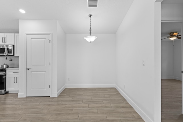 unfurnished dining area with ceiling fan and light hardwood / wood-style floors