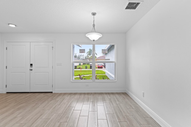 interior space with light wood-type flooring and a textured ceiling