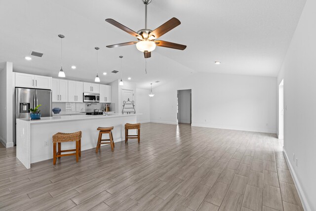 kitchen with ceiling fan, lofted ceiling, light hardwood / wood-style flooring, white cabinetry, and appliances with stainless steel finishes