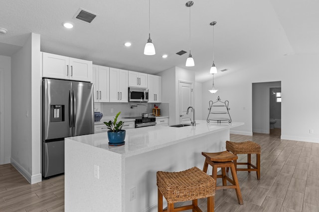 kitchen featuring a center island with sink, stainless steel appliances, sink, and white cabinetry