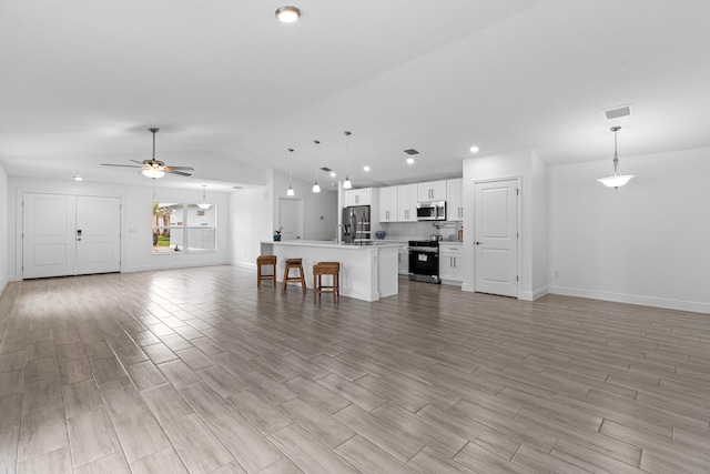 unfurnished living room featuring ceiling fan, light wood-type flooring, lofted ceiling, and sink