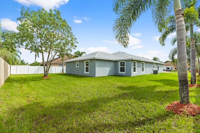 rear view of property featuring a lawn and central air condition unit