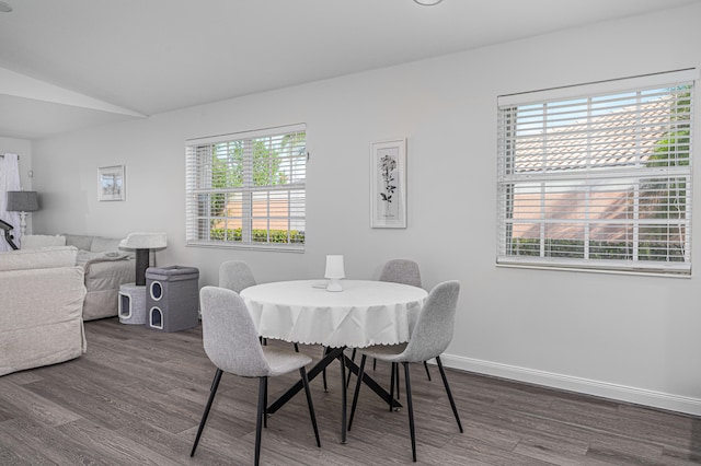 dining area with a healthy amount of sunlight, lofted ceiling, and dark hardwood / wood-style floors