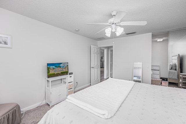 carpeted bedroom with a closet, ceiling fan, and a textured ceiling