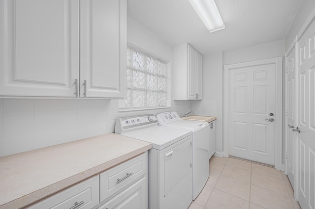 washroom with independent washer and dryer, light tile patterned flooring, a textured ceiling, and cabinets