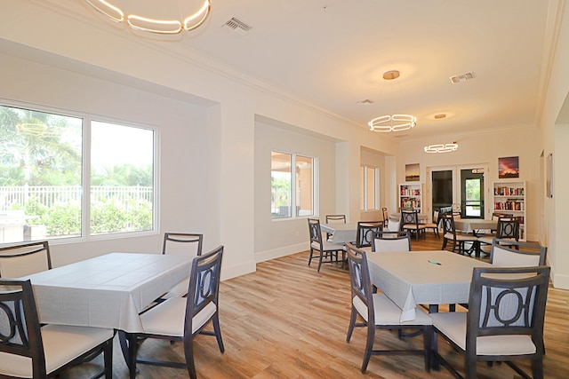 dining room featuring an inviting chandelier, ornamental molding, and light hardwood / wood-style floors