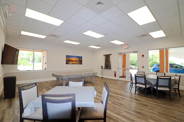 dining room featuring a drop ceiling, wood-type flooring, and plenty of natural light