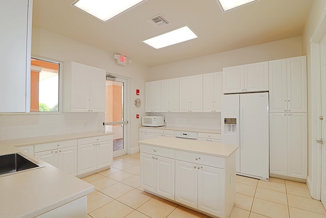 kitchen with white appliances, white cabinetry, and light tile patterned flooring