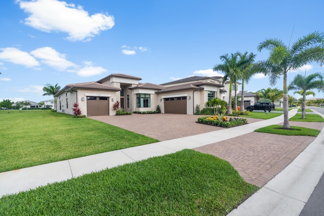 prairie-style home with an attached garage, a front lawn, decorative driveway, and stucco siding