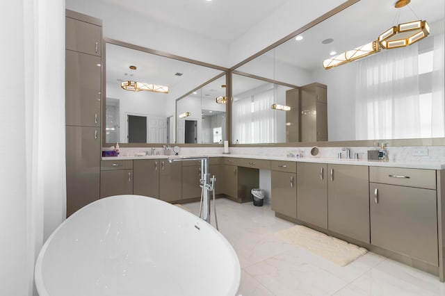 bathroom featuring marble finish floor, a freestanding tub, and vanity