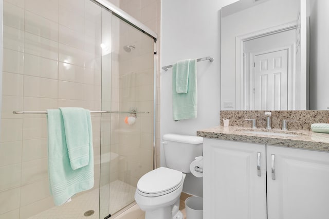 bathroom featuring vanity, a shower stall, and toilet