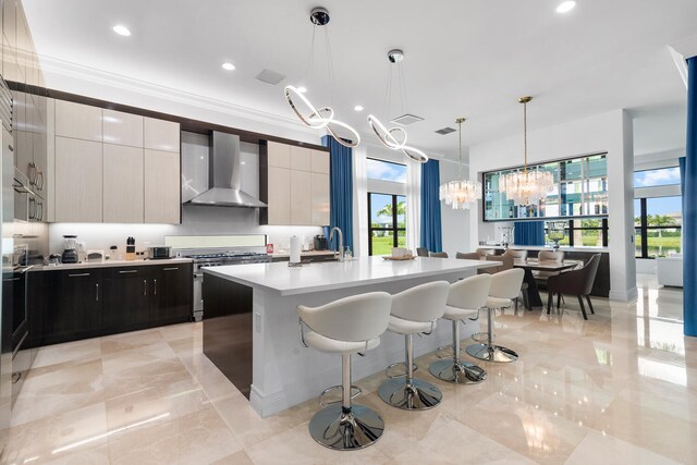 kitchen with a kitchen island with sink, light countertops, wall chimney exhaust hood, stainless steel range, and modern cabinets