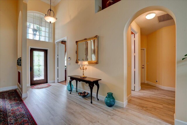 9863 Royal Cardigan Way, West Palm Beach, FL 33411 - dining space with a towering ceiling, baseboards, wood finished floors, arched walkways, and a chandelier