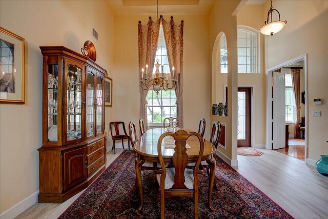 9863 Royal Cardigan Way, West Palm Beach, FL 33411 - dining space with arched walkways, baseboards, a towering ceiling, wood finished floors, and a chandelier