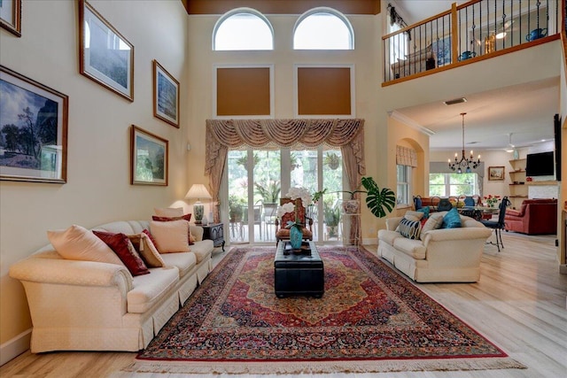 living room featuring ornamental molding, a towering ceiling, light hardwood / wood-style floors, and a wealth of natural light