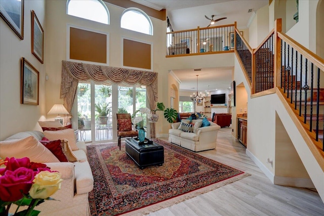 living room featuring a notable chandelier, light hardwood / wood-style flooring, plenty of natural light, and a high ceiling