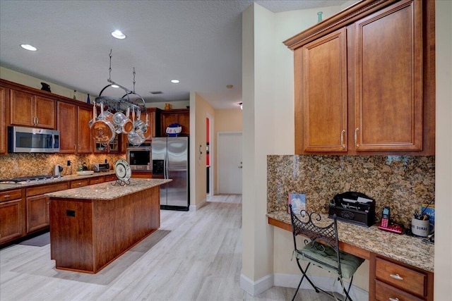 kitchen featuring stainless steel appliances, light stone countertops, light hardwood / wood-style floors, and a center island