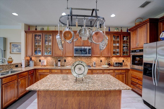 kitchen with appliances with stainless steel finishes, a kitchen island, sink, and light hardwood / wood-style flooring