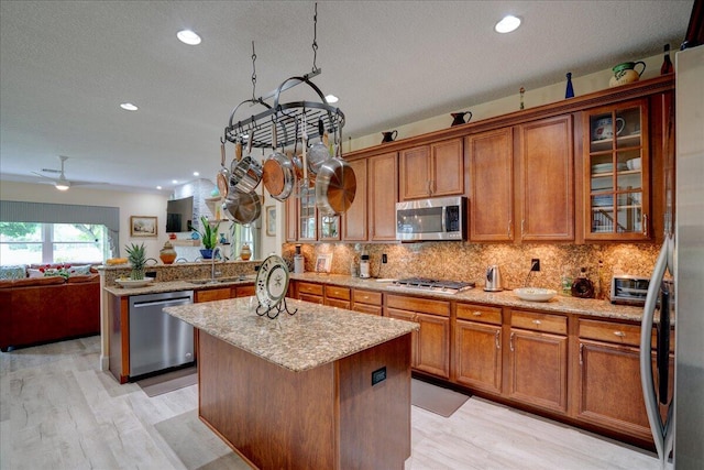 kitchen with a center island, sink, light hardwood / wood-style flooring, appliances with stainless steel finishes, and a textured ceiling