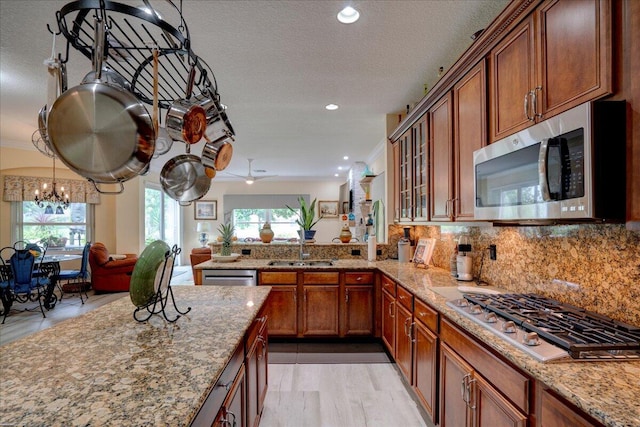 kitchen with sink, kitchen peninsula, light hardwood / wood-style flooring, appliances with stainless steel finishes, and a textured ceiling