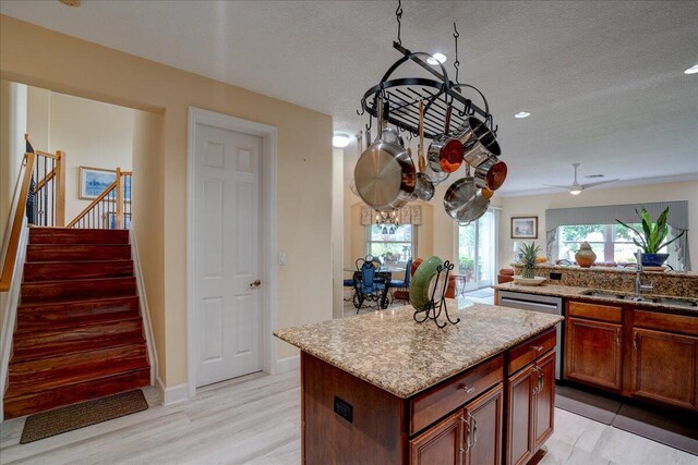9863 Royal Cardigan Way, West Palm Beach, FL 33411 - kitchen featuring a sink, a center island, light stone counters, a textured ceiling, and light wood-style floors