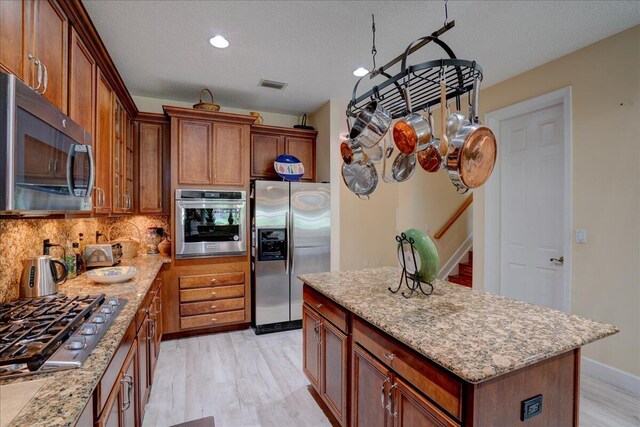 9863 Royal Cardigan Way, West Palm Beach, FL 33411 - kitchen featuring stainless steel appliances, tasteful backsplash, brown cabinetry, and light stone countertops