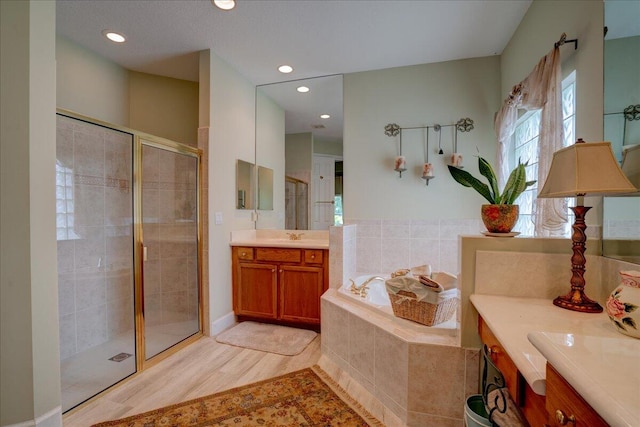 bathroom featuring separate shower and tub, hardwood / wood-style flooring, and vanity