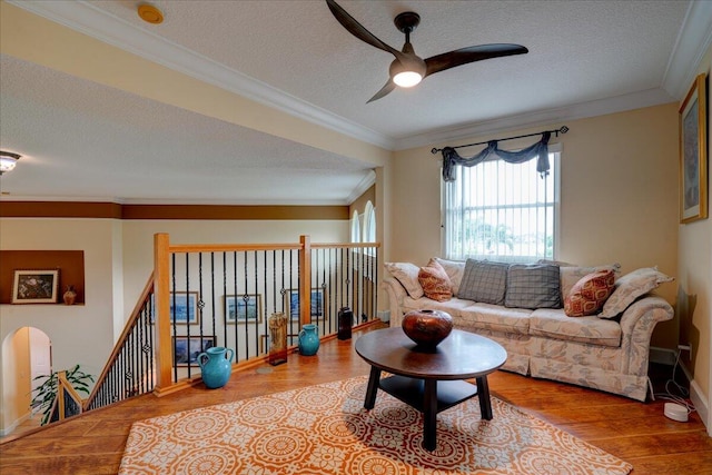 living room with light wood-type flooring, crown molding, ceiling fan, and a textured ceiling