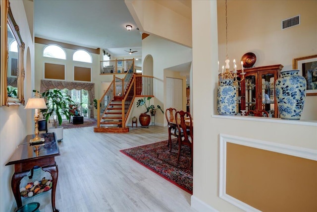 entryway with ceiling fan with notable chandelier, a high ceiling, and hardwood / wood-style flooring