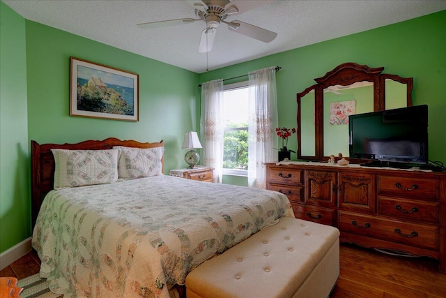 bedroom with ceiling fan, hardwood / wood-style flooring, and a textured ceiling