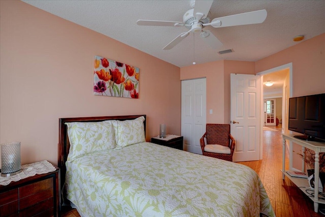 bedroom with ceiling fan, a textured ceiling, a closet, and hardwood / wood-style floors