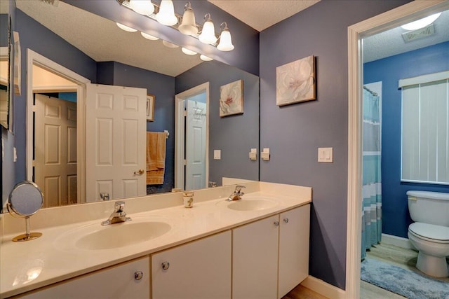 bathroom with vanity, toilet, a shower with shower curtain, and a textured ceiling