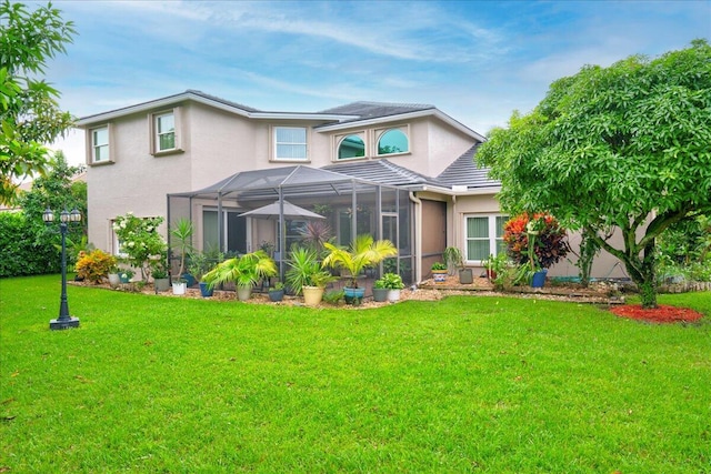 rear view of house with a lawn and a lanai