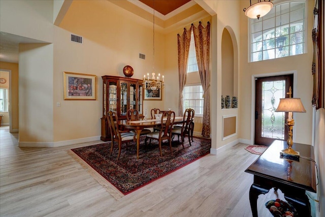 dining area featuring crown molding, a high ceiling, light hardwood / wood-style flooring, and a healthy amount of sunlight