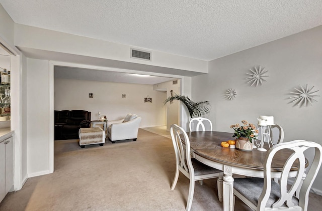 dining area featuring light carpet and a textured ceiling