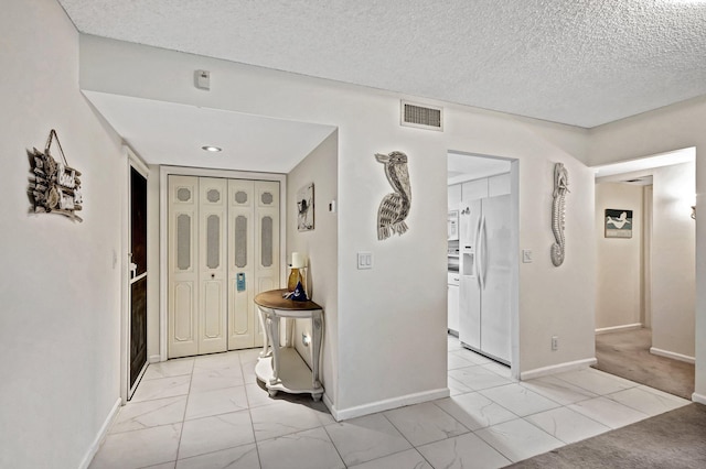 entrance foyer featuring a textured ceiling and light colored carpet