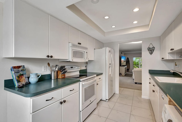 kitchen featuring washer / clothes dryer, sink, a raised ceiling, white cabinets, and white appliances